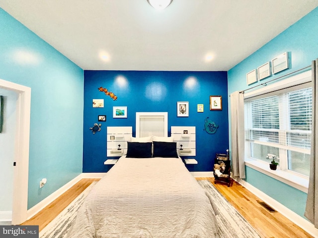 bedroom featuring visible vents, baseboards, and wood finished floors