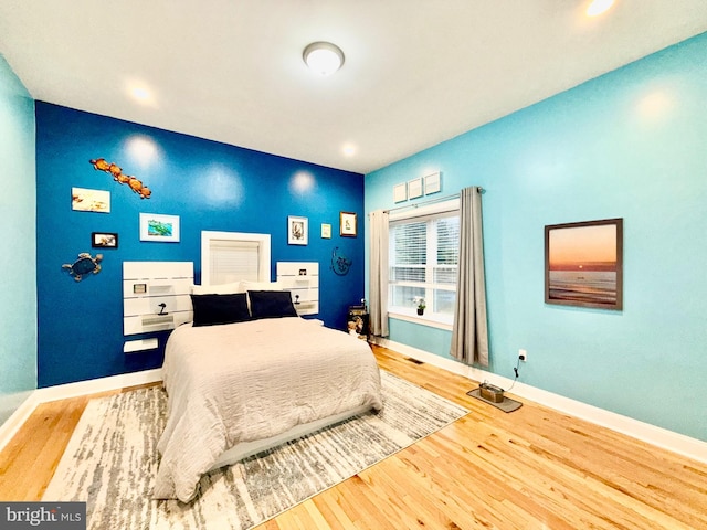 bedroom with visible vents, baseboards, and wood finished floors