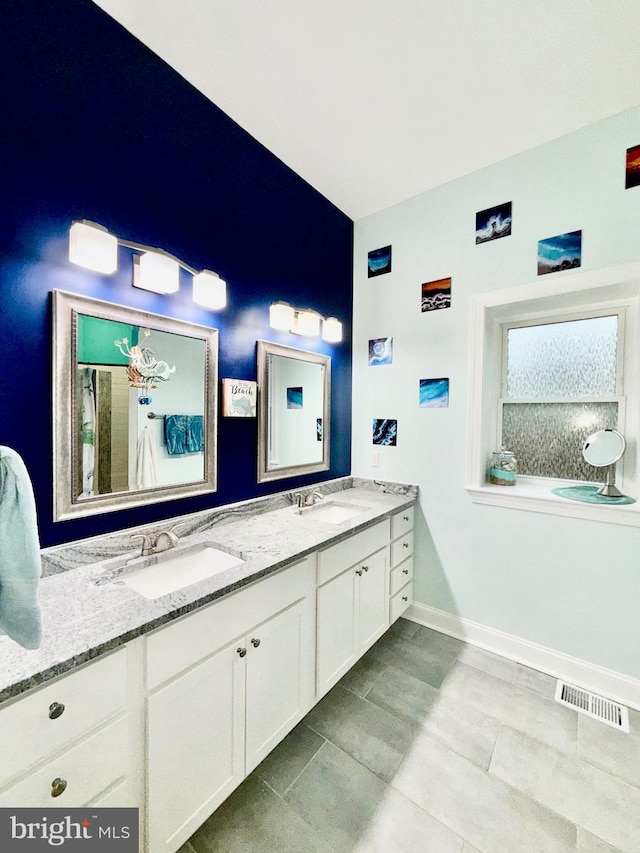 bathroom with double vanity, baseboards, visible vents, and a sink