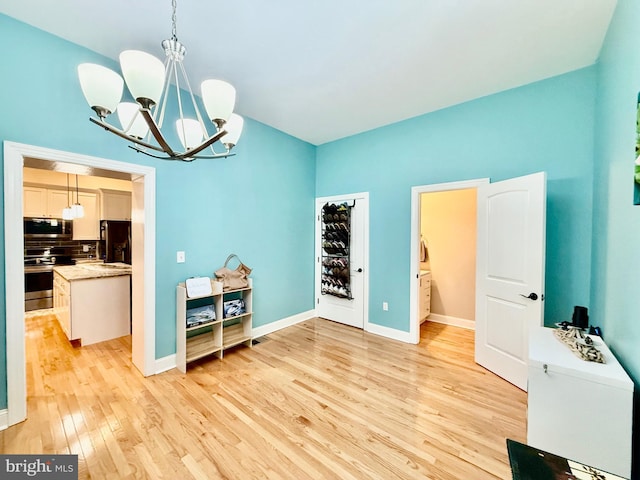 dining area featuring an inviting chandelier, baseboards, and light wood-style floors