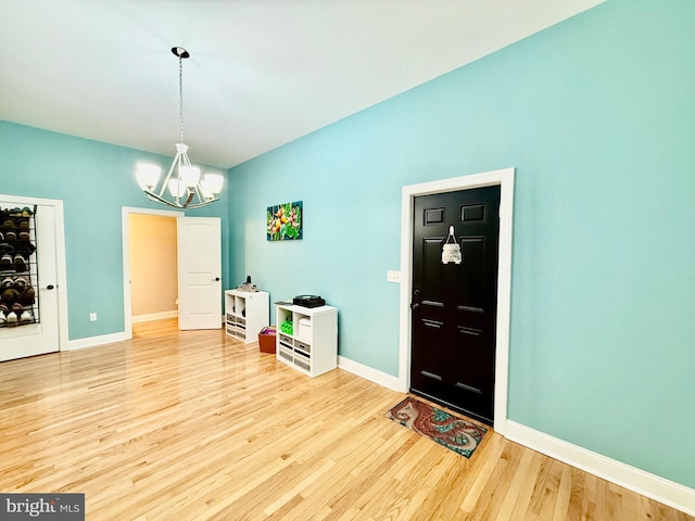 entryway with an inviting chandelier, wood finished floors, and baseboards