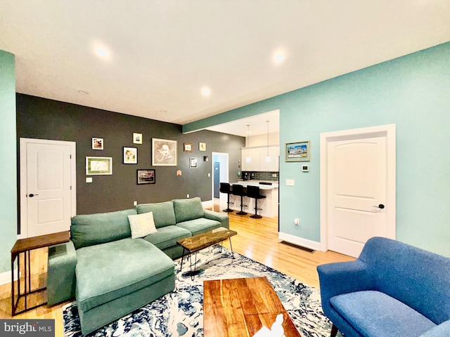 living area featuring recessed lighting, baseboards, and light wood finished floors