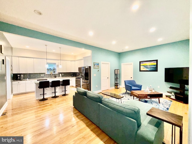 living room featuring recessed lighting, baseboards, and light wood finished floors