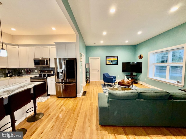 living area with recessed lighting, light wood-type flooring, and baseboards