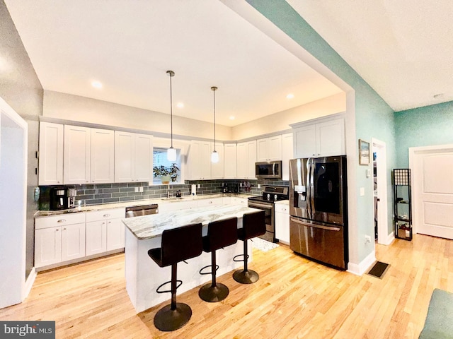 kitchen featuring a center island, light wood-style flooring, stainless steel appliances, and a sink