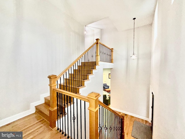 staircase featuring wood finished floors and baseboards