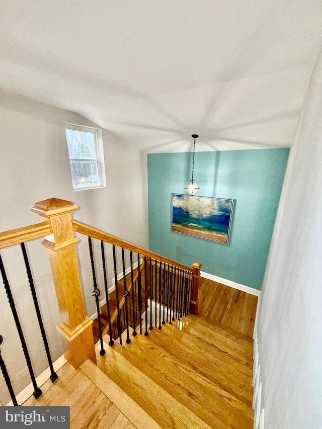 stairs featuring baseboards, wood finished floors, and vaulted ceiling