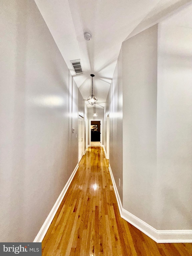 corridor with visible vents, baseboards, and hardwood / wood-style floors