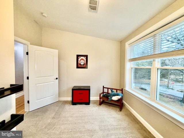 sitting room with visible vents, light colored carpet, baseboards, and lofted ceiling