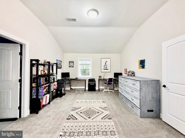 office area featuring lofted ceiling, visible vents, and light carpet