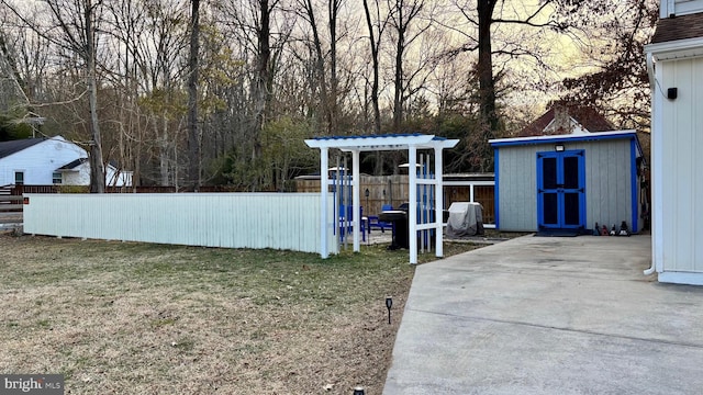 view of yard with an outdoor structure, a storage unit, fence, and a patio area