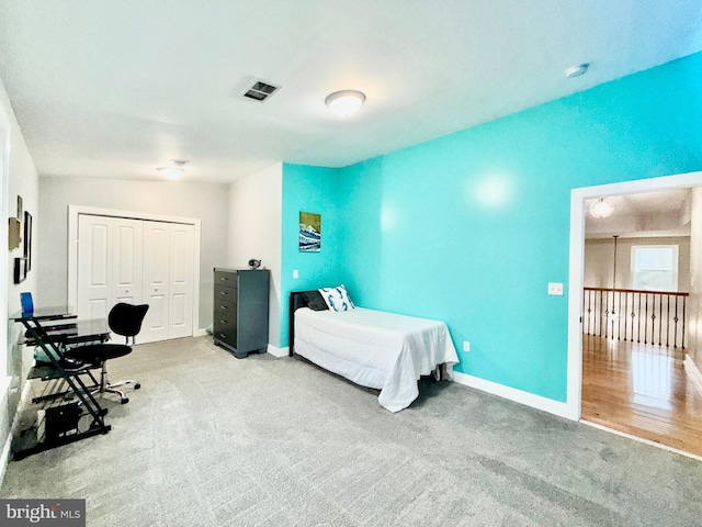 carpeted bedroom with visible vents, baseboards, and a closet