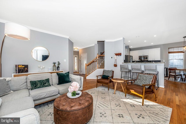 living area featuring light wood-style floors, recessed lighting, crown molding, and stairs