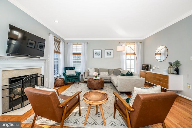 living area with ornamental molding, light wood finished floors, a high end fireplace, and a healthy amount of sunlight