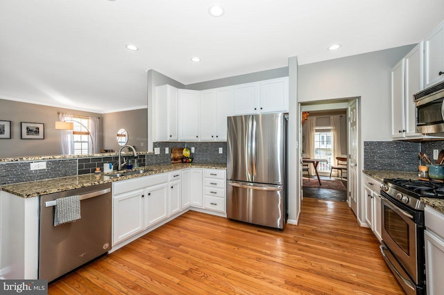 kitchen featuring light wood finished floors, white cabinetry, stainless steel appliances, and a sink