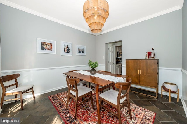 dining space featuring stone finish floor, crown molding, baseboards, and a notable chandelier