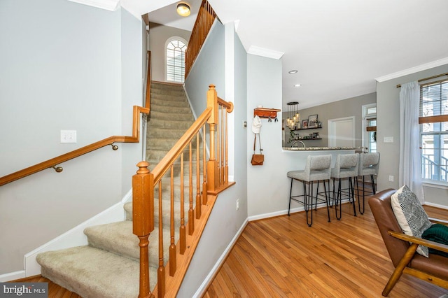 stairway featuring recessed lighting, crown molding, baseboards, and wood finished floors