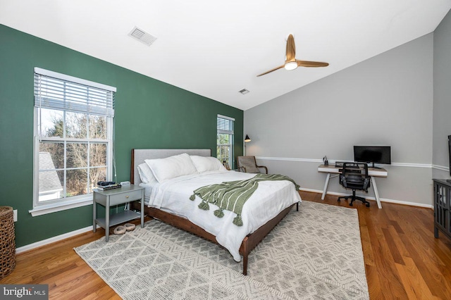 bedroom with lofted ceiling, multiple windows, wood finished floors, and visible vents