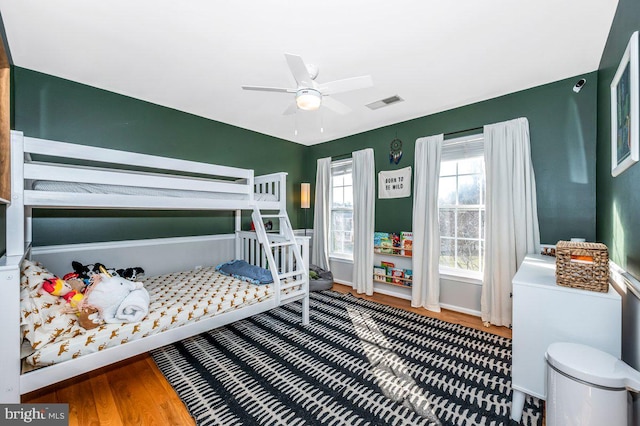 bedroom with wood finished floors, visible vents, and baseboards