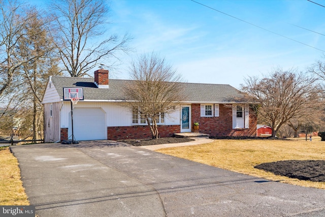 view of front of home with brick siding, a chimney, an attached garage, a front yard, and driveway