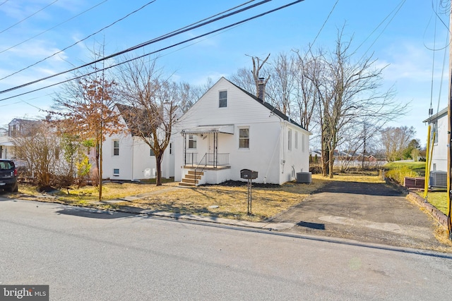 view of front of house with cooling unit, a chimney, and stucco siding