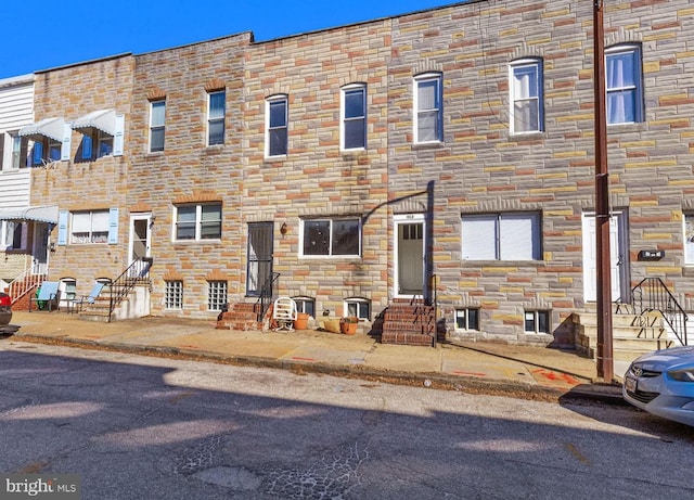 townhome / multi-family property featuring entry steps and stone siding