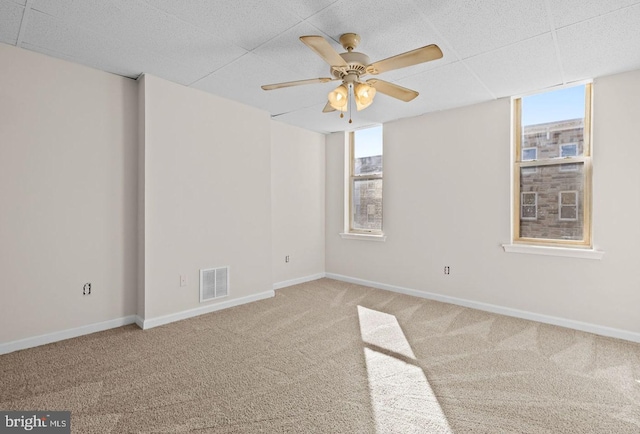 carpeted empty room with baseboards, visible vents, and a ceiling fan