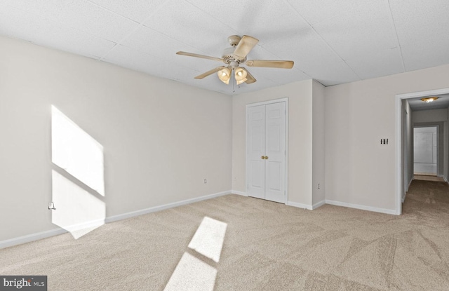 unfurnished bedroom featuring a ceiling fan, a closet, baseboards, and carpet flooring