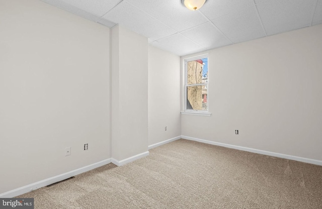 empty room featuring visible vents, carpet flooring, a paneled ceiling, and baseboards