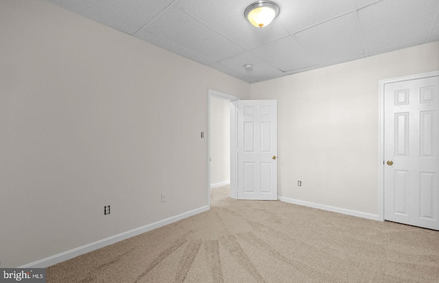 unfurnished room featuring carpet floors, a drop ceiling, and baseboards