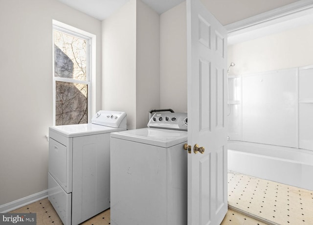 clothes washing area with laundry area, baseboards, light floors, and separate washer and dryer