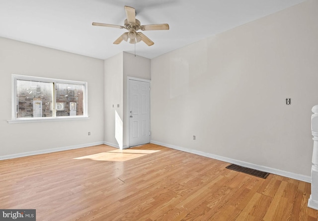 spare room with light wood-type flooring, visible vents, ceiling fan, and baseboards