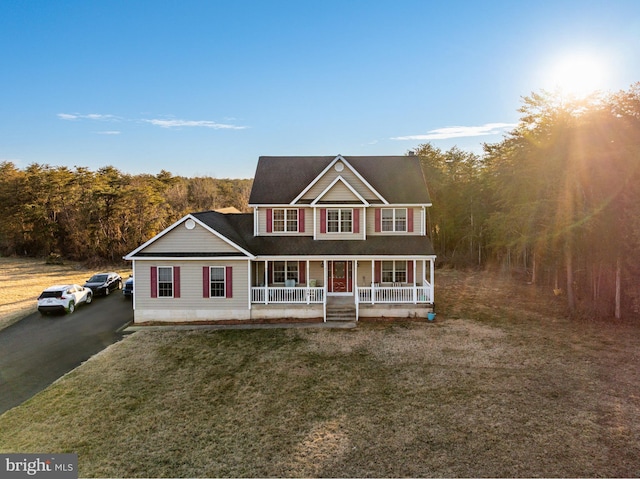 view of front facade with a forest view, a porch, and a front lawn