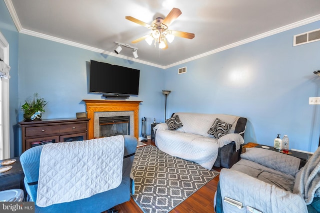 living room with ornamental molding, wood finished floors, a glass covered fireplace, and visible vents