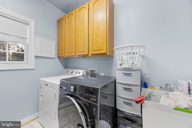 washroom with cabinet space, baseboards, and washer and dryer