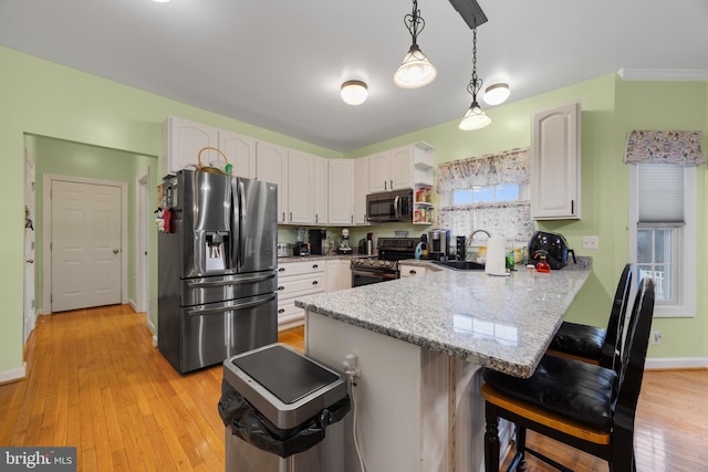 kitchen featuring light stone counters, appliances with stainless steel finishes, a kitchen breakfast bar, a peninsula, and a sink