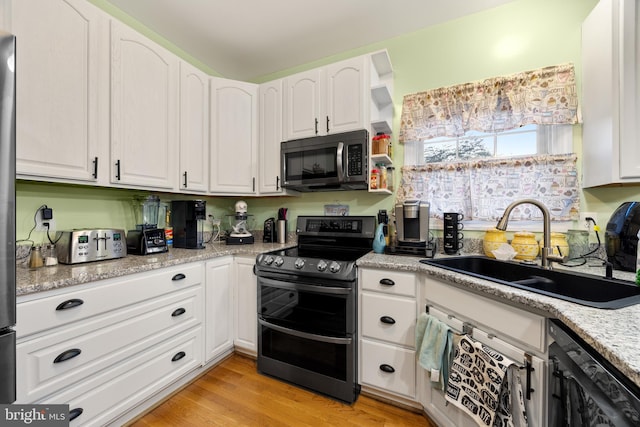 kitchen featuring stainless steel appliances, white cabinetry, a sink, and light wood-style flooring