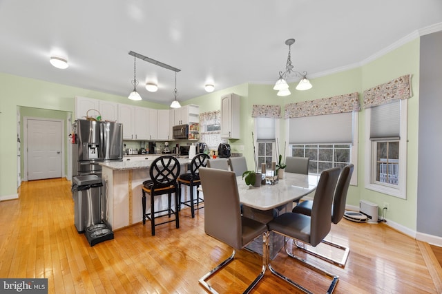 dining room featuring ornamental molding, light wood-style flooring, and baseboards