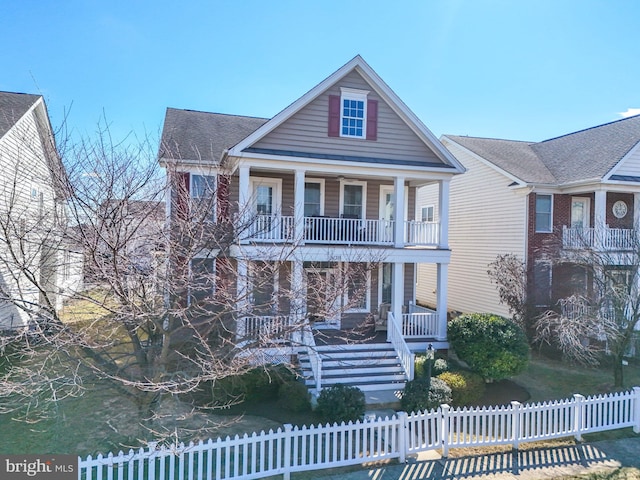 view of front of home with a balcony, covered porch, and a fenced front yard