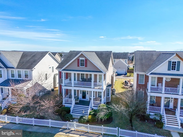 view of front of home with a balcony, covered porch, stairs, a fenced front yard, and a residential view