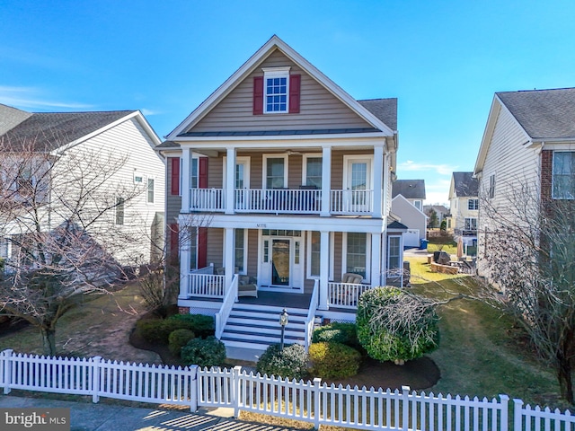 neoclassical / greek revival house featuring a fenced front yard, a balcony, a porch, and a front lawn