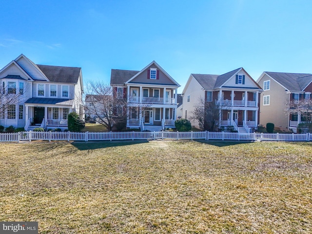 view of front of home with a fenced front yard, a lawn, and a balcony