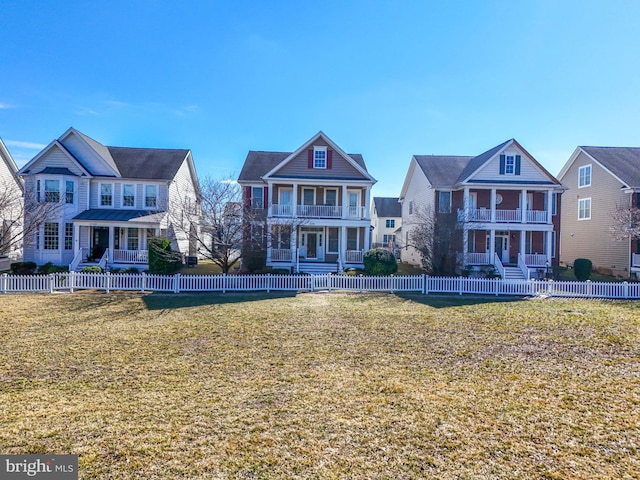 view of front of house featuring a fenced front yard, a residential view, a balcony, and a front lawn