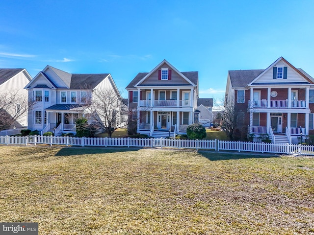 view of front facade with a porch, a balcony, a lawn, and a fenced front yard