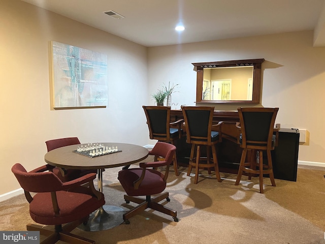 carpeted dining area featuring recessed lighting, visible vents, baseboards, and a bar