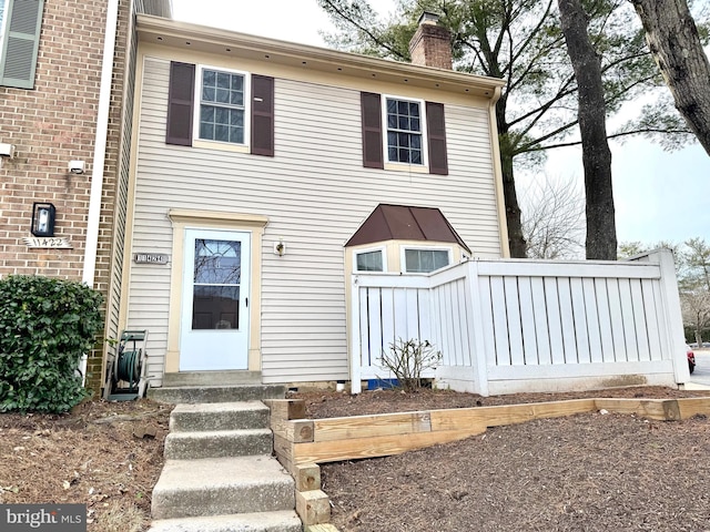 view of front of home with entry steps and a chimney