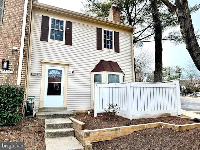 view of front facade with brick siding and a chimney