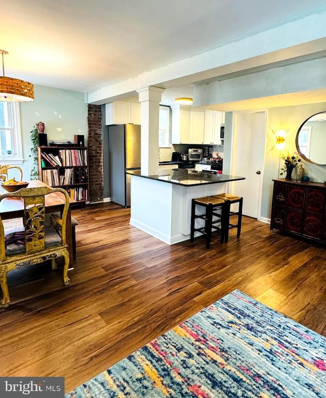 kitchen with white cabinetry, dark countertops, dark wood finished floors, and freestanding refrigerator