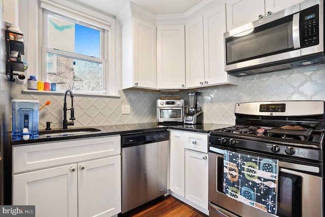 kitchen with a sink, decorative backsplash, stainless steel appliances, white cabinetry, and dark wood-style flooring