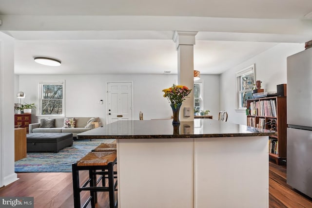 kitchen with dark wood finished floors, freestanding refrigerator, a wealth of natural light, and decorative columns